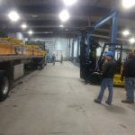 supervisor watching forklift moving crane parts off of truck