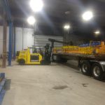 forklift moving acculift crane parts off of truck